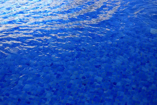 Der Hintergrund ist blaues klares Wasser im Pool mit Wellen und grellem Licht — Stockfoto