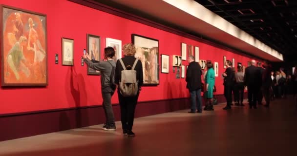 Mensen lopen door de kunstgalerie, kijken naar en bespreken schilderijen — Stockvideo