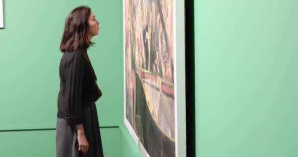 Joven woomen mirando la pintura en la galería de arte con paredes verdes — Vídeos de Stock