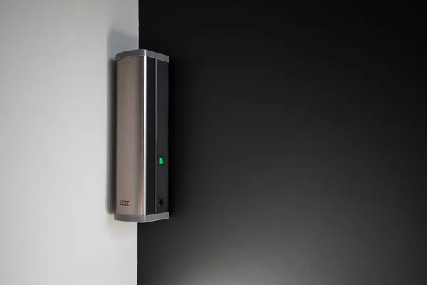 Indoor air purifier in a corner of a room with black and white walls. a working device for cleaning indoor air.