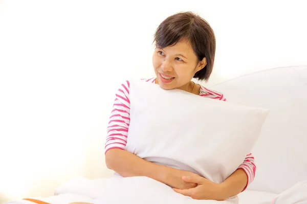 rahat kadın yatağında oturup onun yastık kucaklıyor