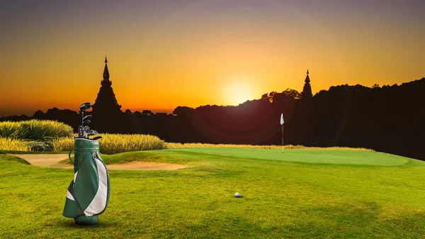 yeşil üzerine golf ekipmanı ve arka plan olarak delik