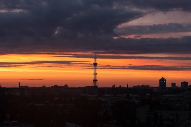 Şehri ele bulutlar ile sıcak gün batımı sırasında yükselen güneş