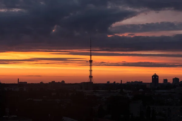 Şehri ele bulutlar ile sıcak gün batımı sırasında yükselen güneş