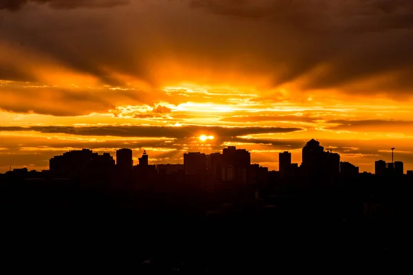 Sun rising over city during warm sunset with clouds