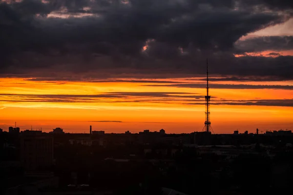 Şehri ele bulutlar ile sıcak gün batımı sırasında yükselen güneş