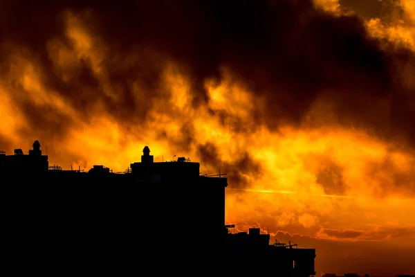 Sol nascendo sobre a cidade durante o pôr do sol quente com nuvens — Fotografia de Stock