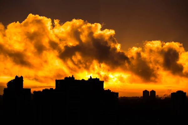 Sun rising over city during warm sunset with clouds