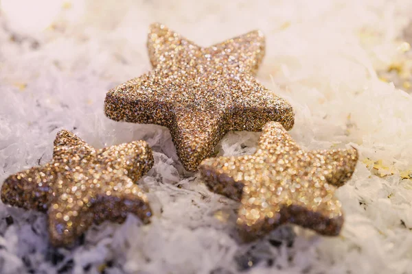 Stock image three glittery stars on white background, shiny warm color photo, focus on the big star