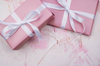 Açık pembe arkaplan ve fotokopi alanı olan beyaz kurdeleli iki pembe hediyenin yatay renkli fotoğrafı