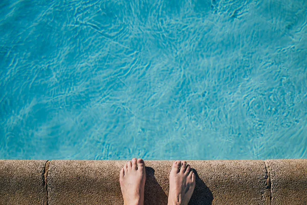 bare feet on the edge of a swimming pool, color photo with copy space