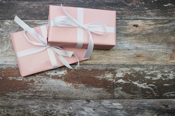Vista desde arriba en dos regalos de color rosa en la superficie de madera marrón con espacio de copia — Foto de Stock