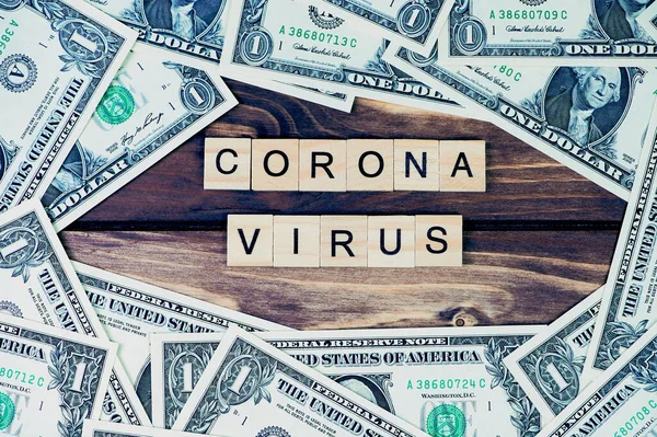 Coronavirus sözcüğü ahşap harflerle yazılıydı. Etrafta bir dolarlık banknotlar vardı.