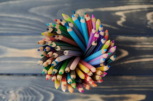 colored pencils in a pencil cup on wooden table, close up photo, view from above