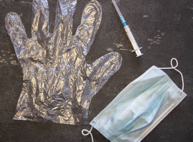 Şeffaf eldivenler, tıbbi maske ve siyah arka planda tıbbi bir şırınga. Coronavirüs ve grip ilacı.