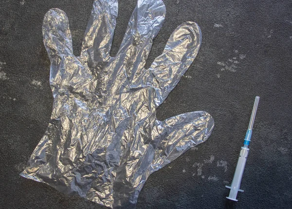 Transparent gloves and a medical syringe on a black background. Coronavirus and flu remedy.