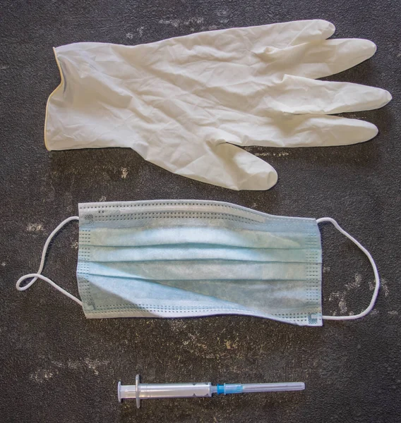 Coronavirus ve grip kontrolü. Tıbbi maske, siyah arka planda iğne ve lastik eldivenli şırınga.. 
