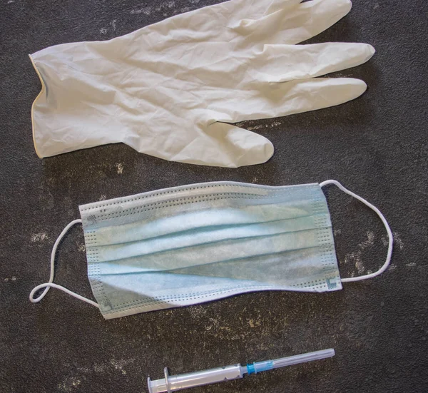 Coronavirus ve grip kontrolü. Tıbbi maske, siyah arka planda iğne ve lastik eldivenli şırınga.. 