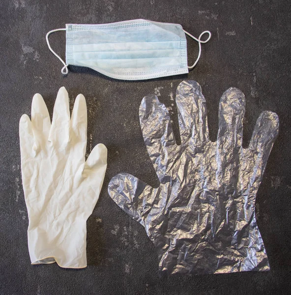 Transparent gloves, a medical mask and rubber medical gloves on a black background. Coronavirus and flu remedy.