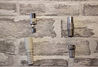 Tuğla bir duvarın arkasındaki televizyondaki anten için metal ve plastik fiş.