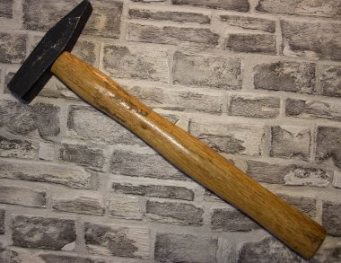 Kara metal çekiç, tuğla bir duvarda ahşap sapı var.