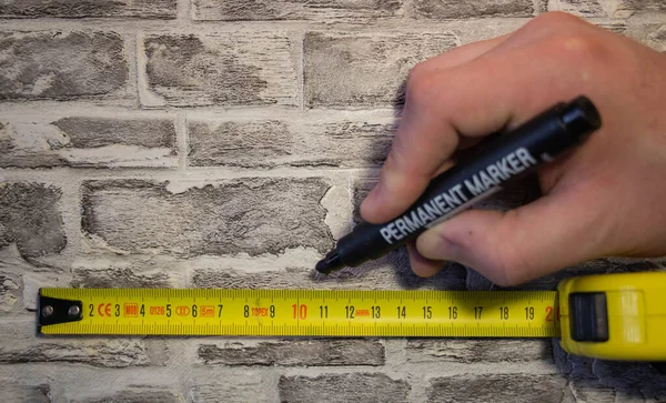 We measure the yellow roll on a brick wall and make marks with a marker for further work