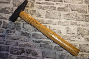 Kara metal çekiç, tuğla bir duvarda ahşap sapı var.