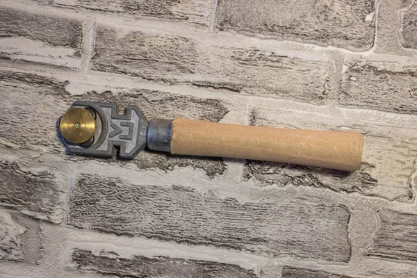 レンガの壁の背景に木製のハンドルを持つ手動ガラスカッター — ストック写真