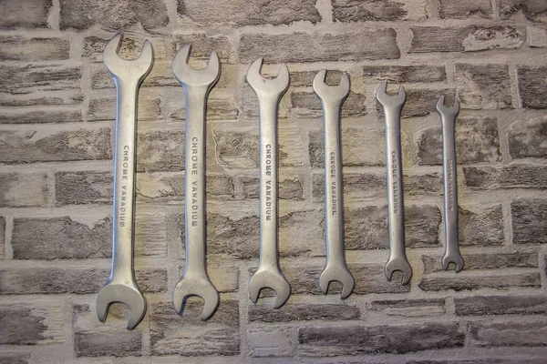 Set of open-end wrenches under the nuts on a brick wall background.