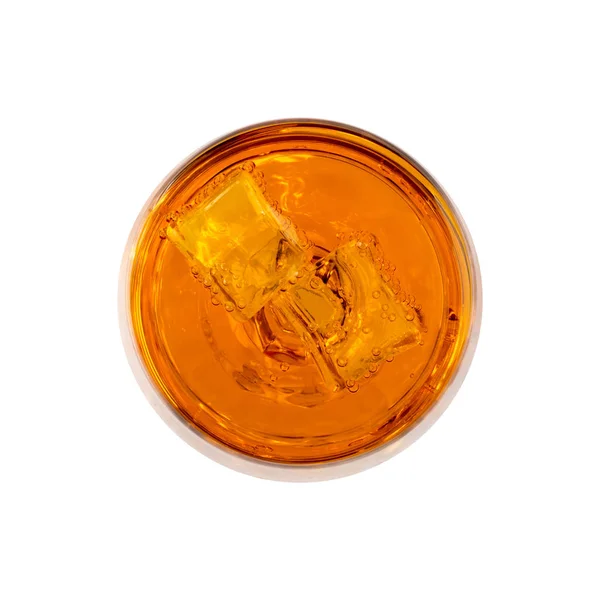 Orange carbonated drink in a glass and ice, close-up on a white background.