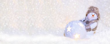 Web afişi için resim. Örgü şapkalı oyuncak kardan adam, beyaz arka planda parlak bir top var. Selamlama, afiş, kartpostal, reklam, fotokopi alanı, metin için yer, ön görünüm için yeni yıl ve Noel arkaplanı