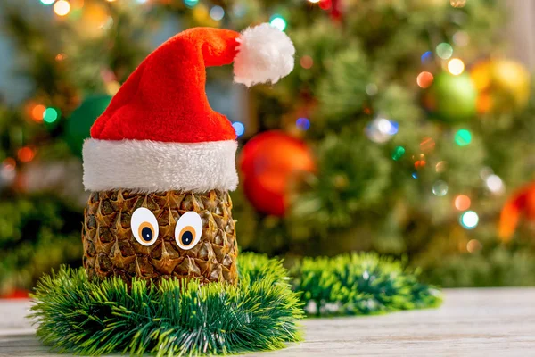 Ananas Mit Augen Hut Des Weihnachtsmannes Großaufnahme Auf Dem Hintergrund — Stockfoto