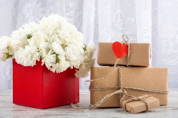 White roses in a red square box and gift boxes craft close-up. Valentine's day, wedding, declaration of love. Space for text, front view, copy space.