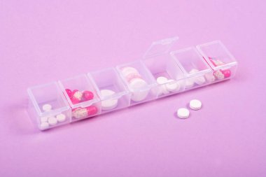 Pembe arka planda haplar için hücreleri olan plastik bir kutu. Haftanın günlerinin tedavi çizelgesi, hastalık için haplar, düz yatak, mesaj için yer, uzay kopyası.