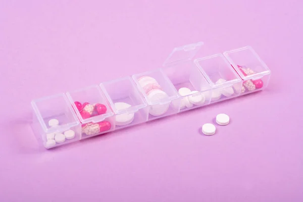 ピンクの背景に丸薬のための細胞とプラスチック製の箱 病気のための丸薬と週の日の治療スケジュール フラットレイ テキストのための場所 コピースペース — ストック写真