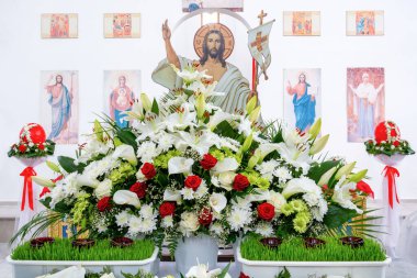 Orlovshchina, Ukrayna, Ortodoks Kilisesi, 04.28.2019. Büyük Paskalya kutlaması. Gonfalonlu Hz. İsa 'nın görüntüsü farklı çiçek buketleri ve kemer ile süslenmiş bir mezarın üzerinde duruyor..