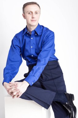 Genç yetişkinler kavramları. Mavi gömlek ve koyu mavi Chinos poz katlanmış ellerle yakışıklı beyaz adam portresi