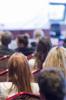 Conference.Vertical görüntü sırasında belgili tanımlık büyük perde önünde oturan insanlar