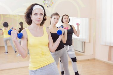 Barbell ile bir egzersiz eğitim sahip üç beyaz kadın 