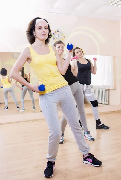 Barbell ile bir egzersiz eğitim kapalı olan üç beyaz kadın