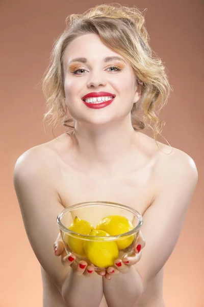 Sexy Fruit Series. Sensual and Naked Caucasian Blond Girl Holding Glass Container With Three Lemons.