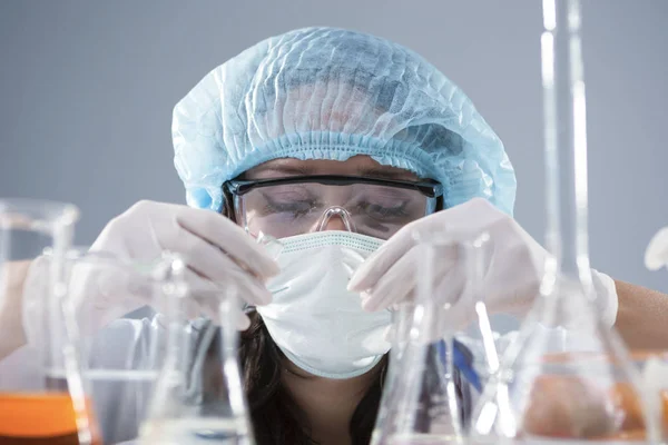 Researching and Science Concepts. Female Laboratory Staff in Facial Mask And Protective Gloves Conducting Experiment