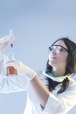 Laboratuvar sıvı bileşenleri ile kadın laboratuvar asistanı olarak bilimsel deney sırasında koruyucu eldivenler