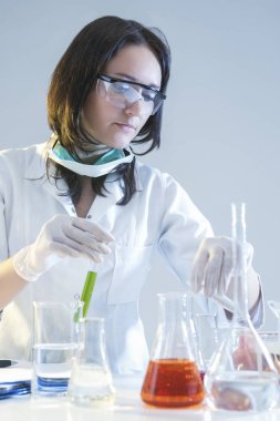 Tıp kavramları. Kadın laboratuvar asistanı olarak bilimsel deney sırasında koruyucu eldivenler