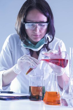 Tıp fikirler ve kavramlar. Kadın laboratuvar çalışan sıvı kimyasal maddelerle dolu şişeler ile