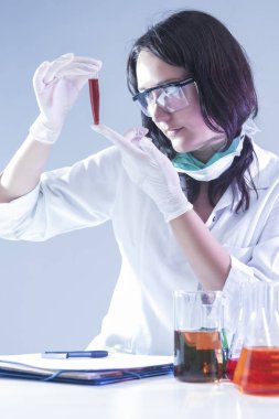 Tıp fikirler ve kavramlar. Kadın laboratuvar alt şişe ile sıvı kimyasal dolu bakarak