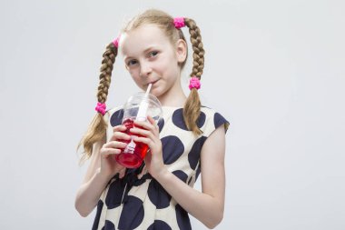 Küçük kızla beyaz puantiyeli elbise içinde ayakta Pigtails gülümseyen portresi 