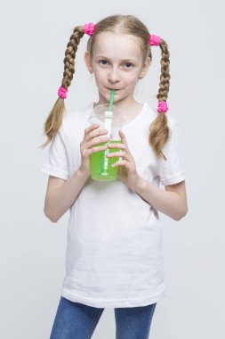 Kupası tutarak ve saman yeşil suyu içme uzun kuyruklu Beyaz sarışın kızla çok gülümseyen portresi.