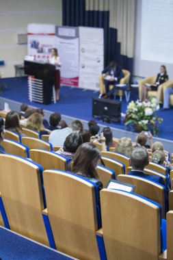 Kadın ana sahne seyirci önünde büyük kongre salonu iş toplantısında konuşan.