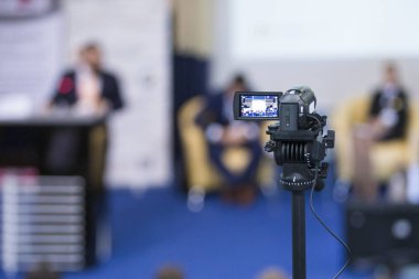 Arkadan görünüşü kompakt Videocamera. Konumlandırılmış karşı bulanık arka plan ile ana bilgisayar konuşan sahnede.